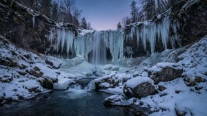 Una impresionante cascada invernal con carámbanos y nieve, bajo un cielo crepuscular estrellado. — 1280x720 Fondos de pantalla