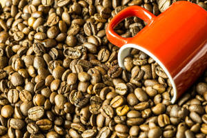 Taza roja grande hundida en los granos de café — Estética café Fondos de pantalla