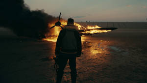 Fondo de pantalla de Tom Hardy como Farrier en la película Dunkerque mirando un avión en llamas.
