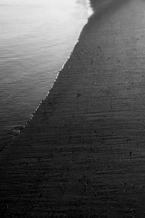 Océano y orilla en blanco y negro con arena gris.