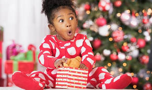 Fondo de pantalla de una niña pequeña sorprendida con un regalo de Navidad — Estética navideña linda Fondos de pantalla