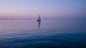 Un velero solitario en aguas tranquilas del océano al atardecer. — Océano Fondos de pantalla